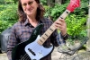 Geddy Lee holding a signed Fender Jazz Bass for Make Music Matters Healing in Harmony Holiday auction.